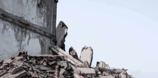 Collapsed concrete building rubble under a clear sky