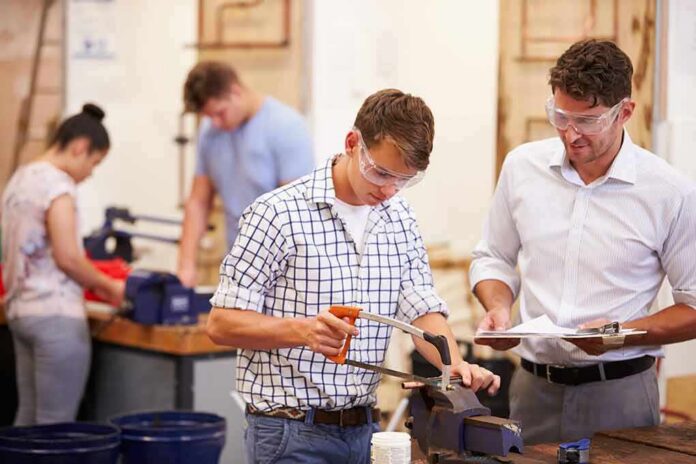 Students using tools in a workshop with instructor supervising