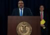Man speaks at podium with New York County District Attorney seal