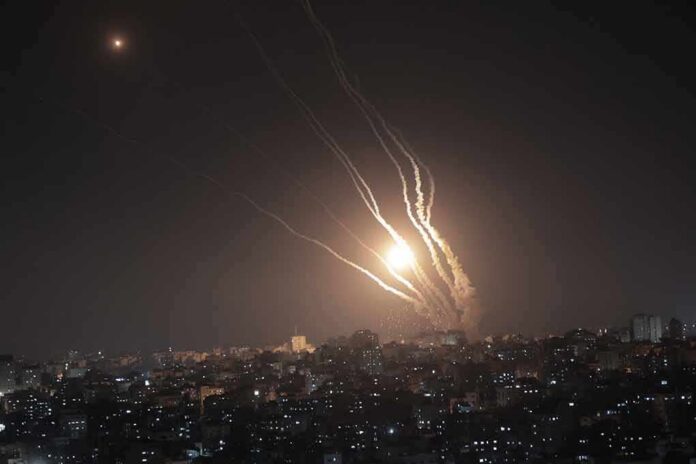 Night sky above a city with multiple rockets arcing and bright explosions