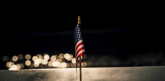 Small American flag on a memorial with bokeh lights at night
