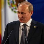 Russia Dangles Talks, Keeps Trigger Pulled Vladimir Putin at a podium during a formal event