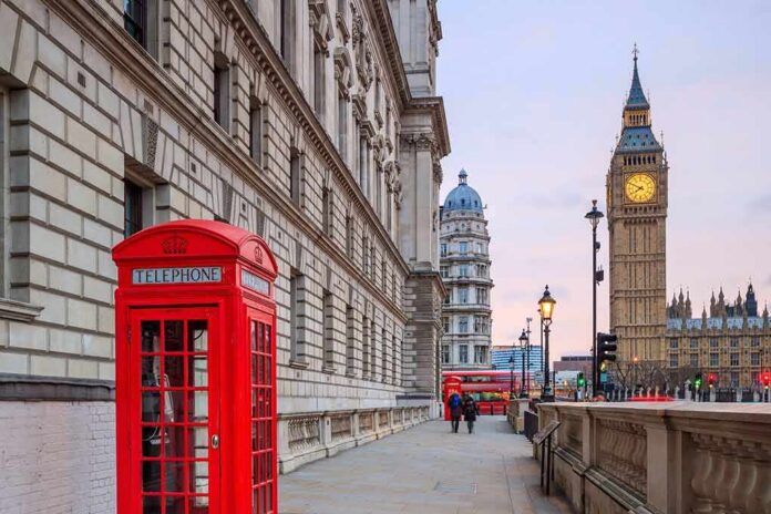 Red telephone box on a London street with clock tower in background