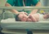 Outrage Erupts Over Infant Discharge Orders Newborn baby in hospital bassinet being cared for by nurse