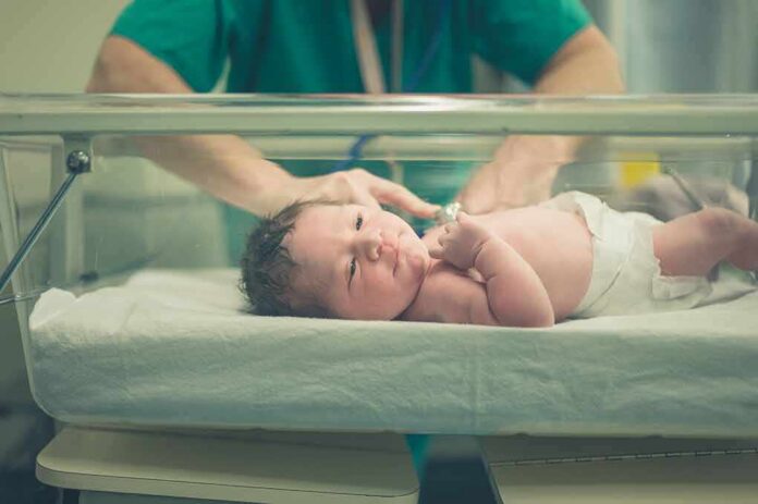 shutterstock_516260941 Newborn baby in hospital bassinet being cared for by nurse