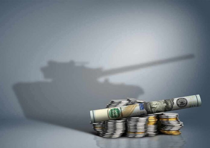 shutterstock_585304205 Stacked coins and rolled banknote with tank shadow in background