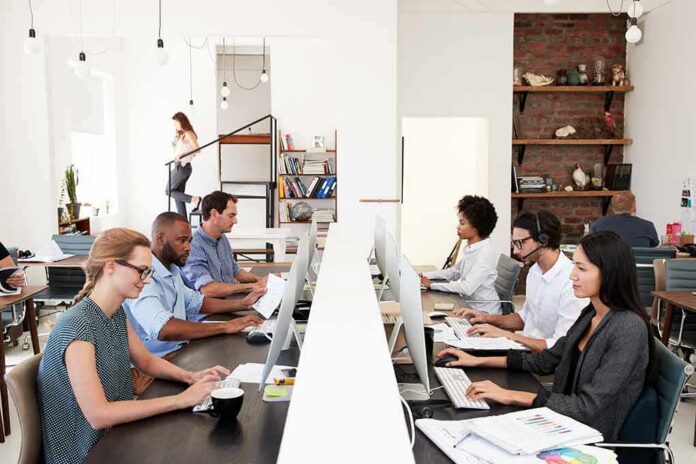 Office workers at shared desks using desktop computers