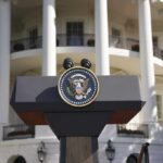 Trump Slaps Privilege On Kennedy Center Presidential podium with seal in front of white-columned building