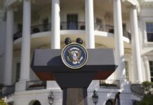 Trump Slaps Privilege On Kennedy Center Presidential podium with seal in front of white-columned building