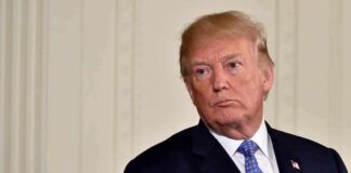 Donald Trump in a dark suit with blue tie looking to the side