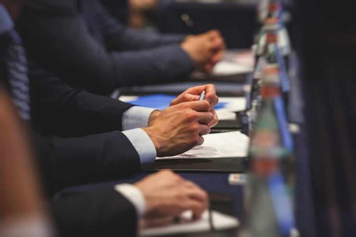 shutterstock_1113307040 Hands of people in suits taking notes at a conference table