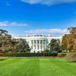 The White House with lawn and gardens under a blue sky