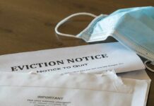 Eviction notice and torn envelope beside blue surgical masks