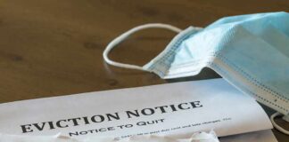 Eviction notice and torn envelope beside blue surgical masks