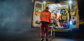 Paramedics load a patient into an ambulance at night