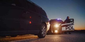 Police officer at patrol car during traffic stop at dusk