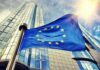 EU Asset Freezes Raise Questions About Free Speech European Union flag waving in front of modern glass office buildings