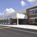 Birthday Gun Twist Upends Oregon Tragedy Modern school building with large windows and a clear sky