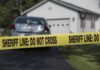 Sheriff line tape blocking a suburban driveway