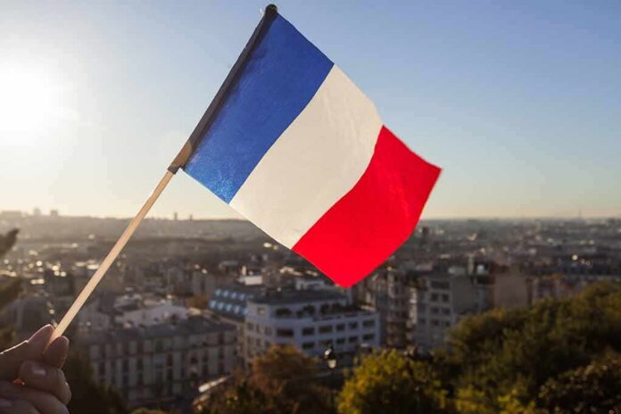 French flag waving over a city skyline at sunset